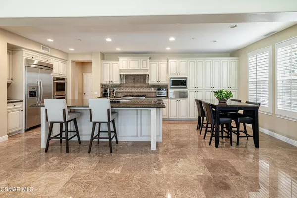 a kitchen with kitchen island granite countertop wooden cabinets and chairs