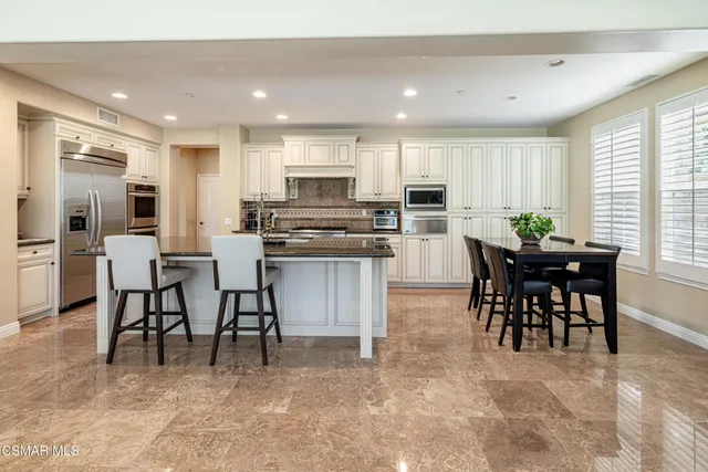 a kitchen with kitchen island granite countertop wooden cabinets and chairs