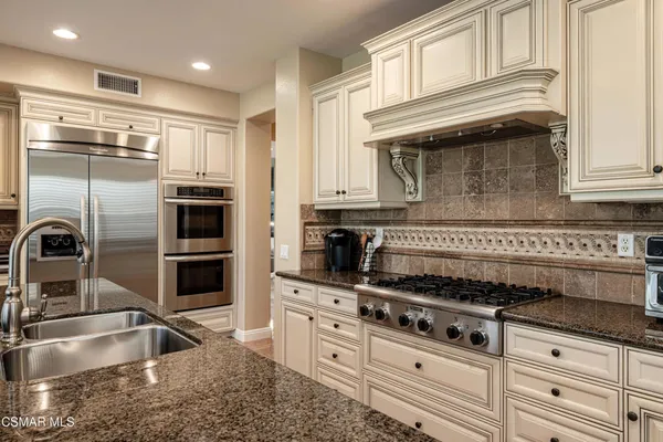 a kitchen with granite countertop a sink stainless steel appliances and cabinets