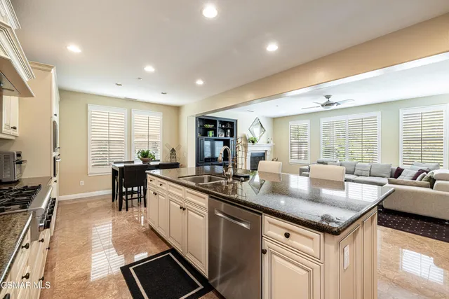 a kitchen with granite countertop a sink a counter top space and living room view