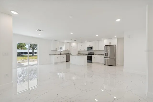 a view of kitchen with kitchen island stainless steel appliances refrigerator sink and cabinets