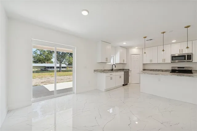a large white kitchen with a stove a sink dishwasher and a refrigerator with white cabinets