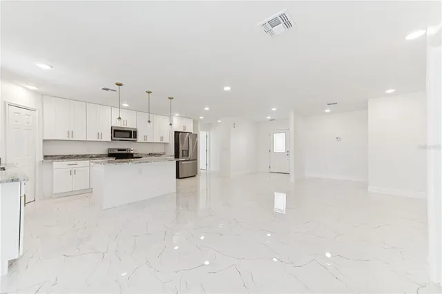 a large kitchen with white cabinets and stainless steel appliances