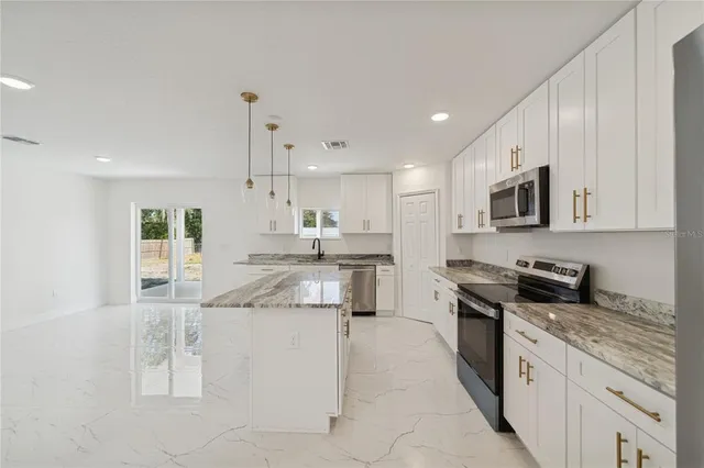 a kitchen with stainless steel appliances granite countertop a stove a sink and a refrigerator