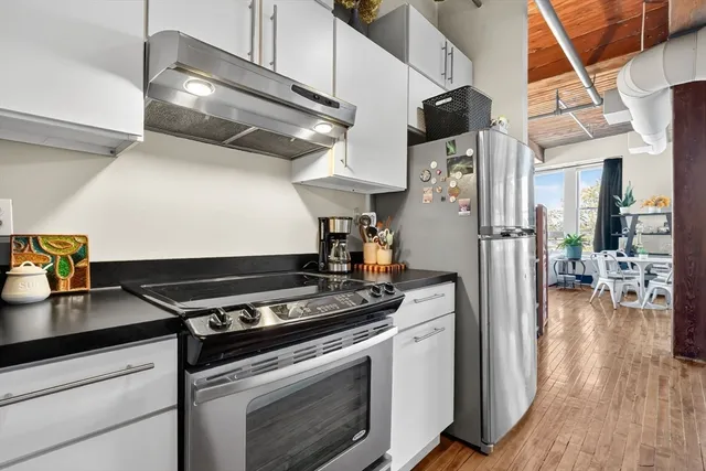 a kitchen with stainless steel appliances granite countertop a stove and a wooden floor