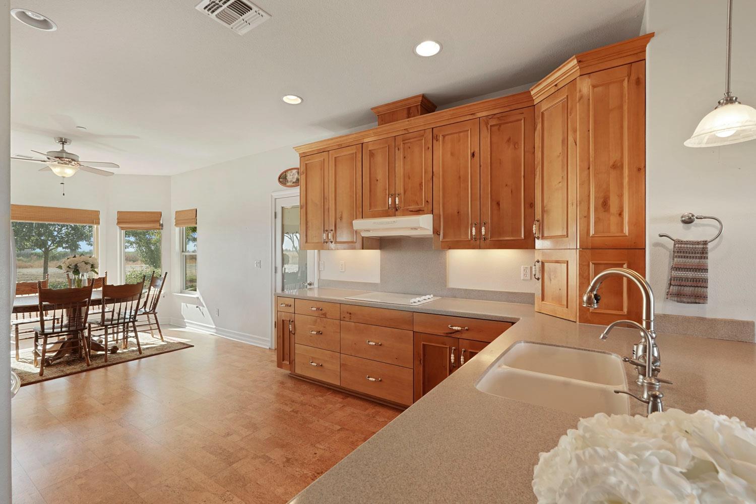 6120 Eschinger Road Elk Grove, CA 95757 - Photo 8 of 39 a kitchen with stainless steel appliances a stove a sink a dining table and chairs with wooden floor