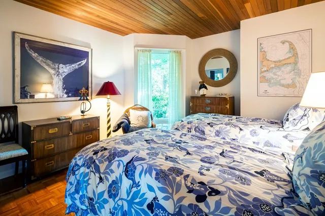 a bedroom with a bed a mirror on dresser and a large window
