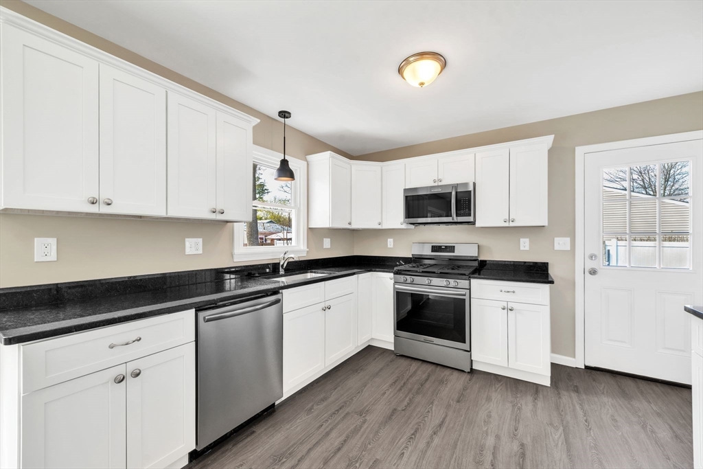 230 Gilbert Avenue Springfield, MA 01119 - Photo 5 of 40 a kitchen with stainless steel appliances granite countertop a stove top oven a sink and white cabinets