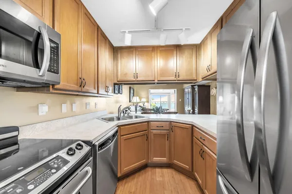 a kitchen with stainless steel appliances granite countertop a sink a stove and a wooden floors