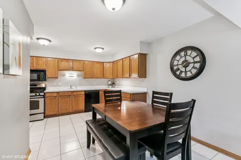a kitchen with granite countertop a table chairs a stove top oven a clock and a window