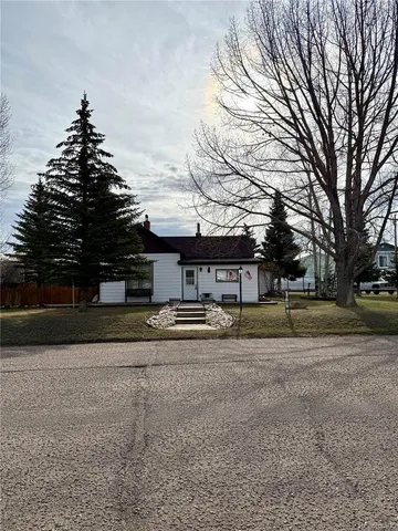 a front view of a house with a yard and trees