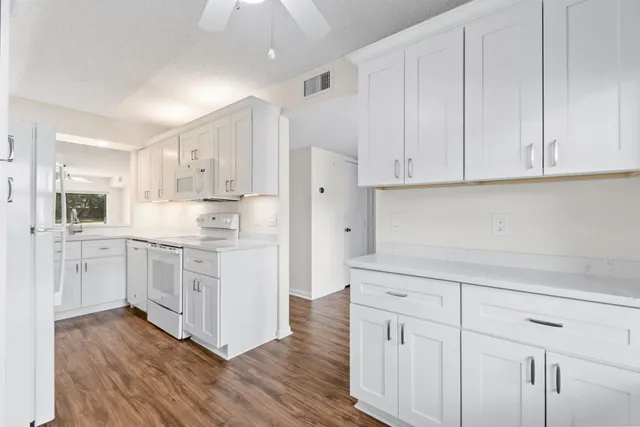 a kitchen with white cabinets and a window