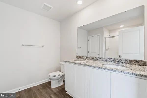 a bathroom with a granite countertop toilet a sink and a mirror
