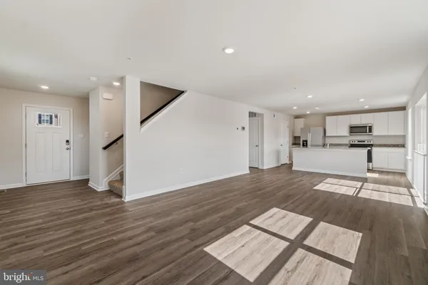 a view of a living room with wooden floor and a kitchen