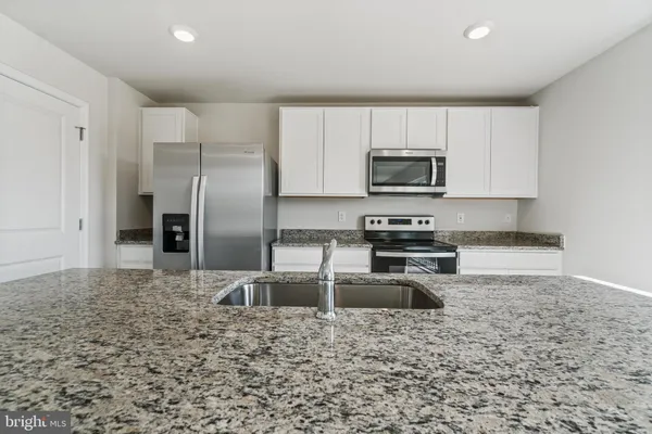 a kitchen with granite countertop a refrigerator and a stove top oven