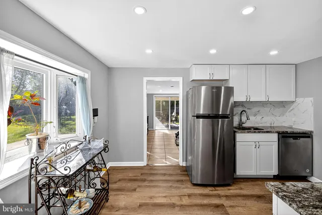 a kitchen with stainless steel appliances granite countertop a refrigerator a stove and a wooden floors