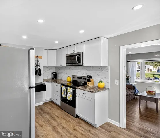 a kitchen with stainless steel appliances a stove a sink cabinets and a wooden floor