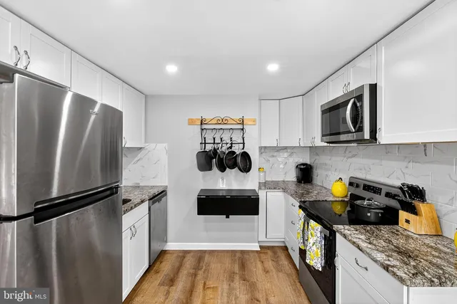 a kitchen with stainless steel appliances granite countertop a refrigerator a stove and a sink