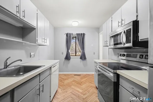 a kitchen with stainless steel appliances granite countertop a sink a stove and a microwave oven with cabinets