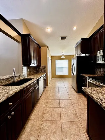 a kitchen with stainless steel appliances granite countertop a refrigerator a stove a sink and dishwasher