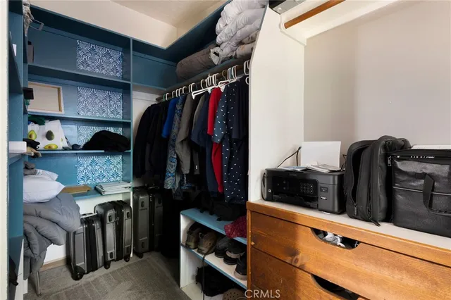 a view of walk in closet with clothes and shoes