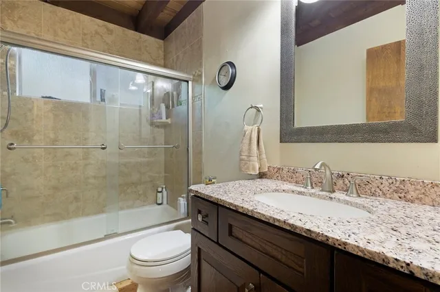 a bathroom with a granite countertop sink a toilet and shower
