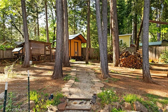 a backyard of a house with large trees and wooden fence