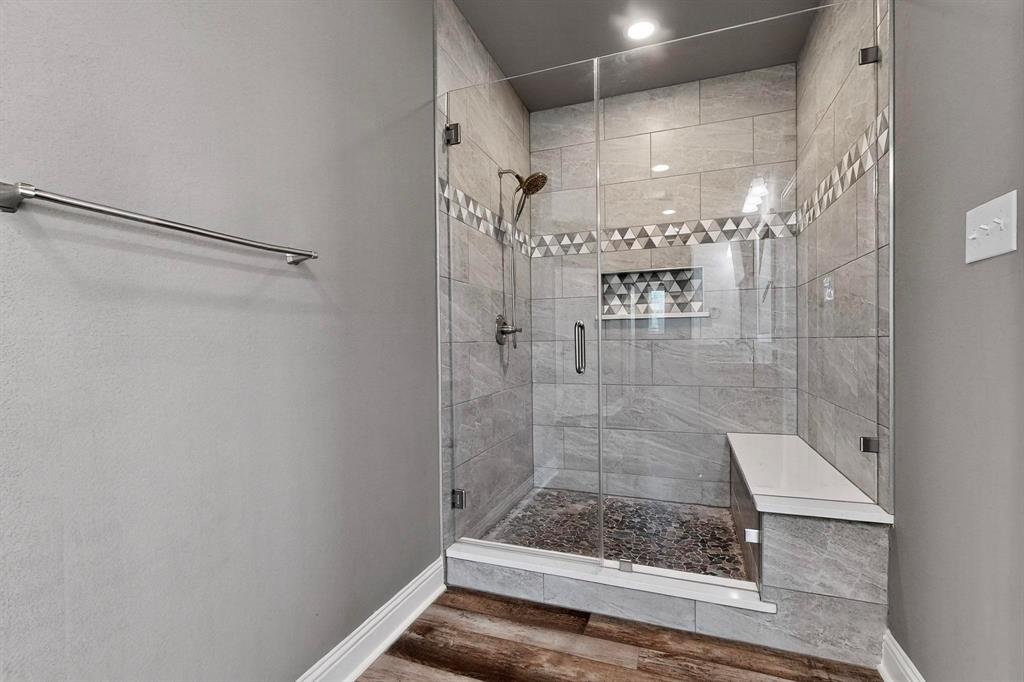 634 Gant Road Sherman, TX 75090 - Photo 23 of 40 Spacious shower with glass enclosure, textured wall tile, mosaic accent band, recessed niche with shelf, and built-in bench