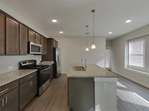 a kitchen with stainless steel appliances granite countertop a sink a stove a refrigerator cabinets and wooden floor