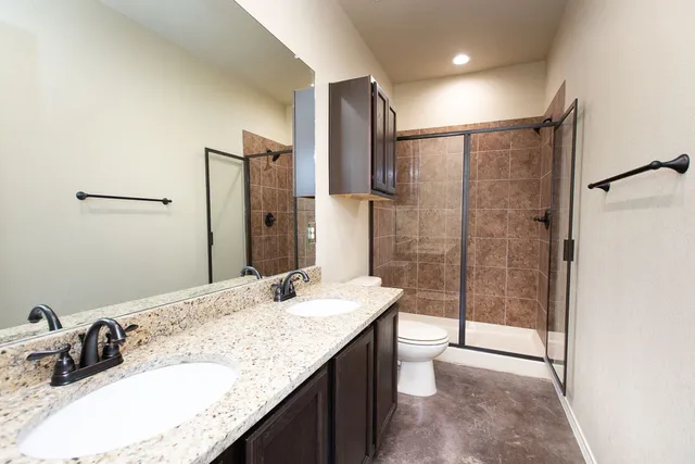 a bathroom with a granite countertop sink a mirror and shower