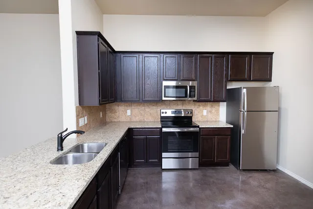 a kitchen with kitchen island granite countertop a sink stainless steel appliances and cabinets