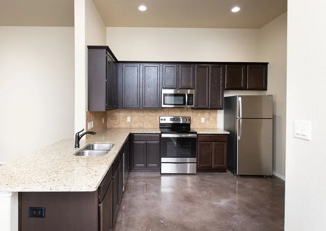 a kitchen with kitchen island granite countertop stainless steel appliances and wooden cabinets