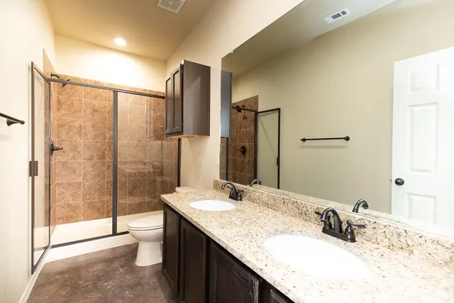 a bathroom with a granite countertop sink a mirror and shower
