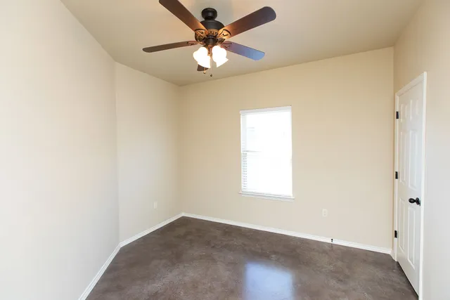 an empty room with a window and a fan
