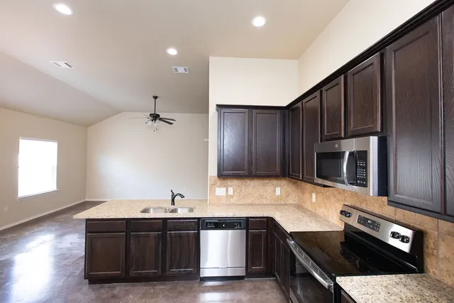 a kitchen with stainless steel appliances granite countertop a stove a sink and a microwave