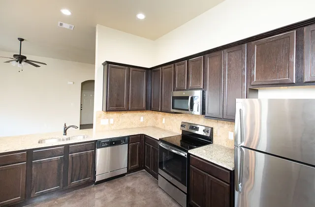 a kitchen with granite countertop stainless steel appliances a refrigerator a sink and cabinets