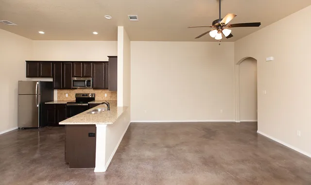 a kitchen with kitchen island a counter top space appliances and a ceiling fan