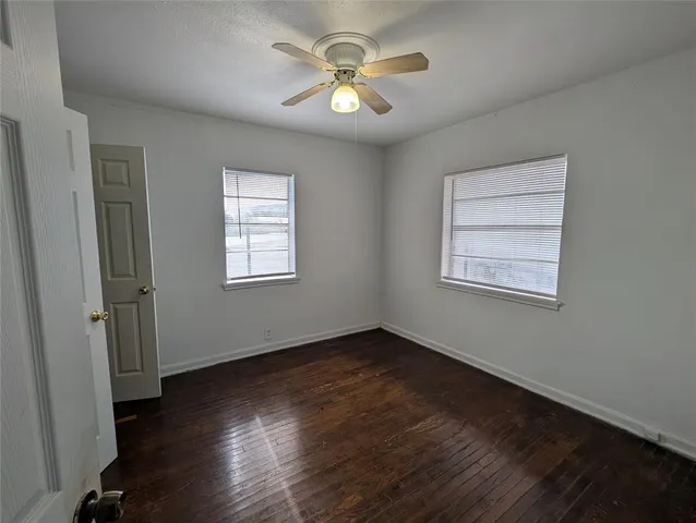 a view of an empty room with window and wooden floor