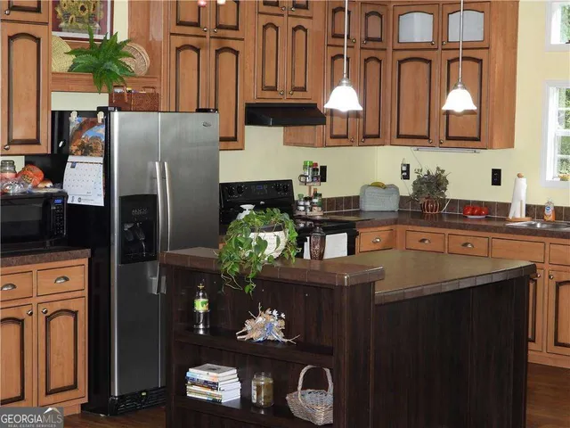 a kitchen with stainless steel appliances granite countertop a sink dishwasher a refrigerator a stove and a dining table with wooden floor