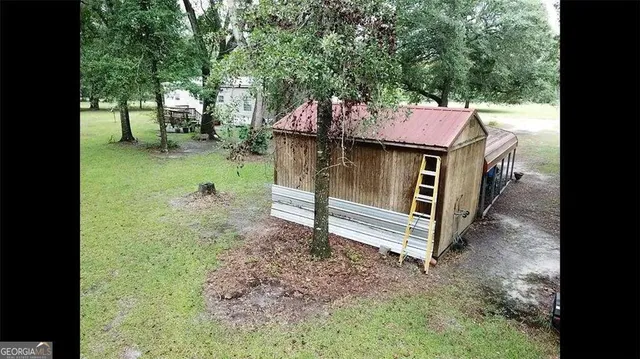 a backyard of a house with wooden fence and large trees