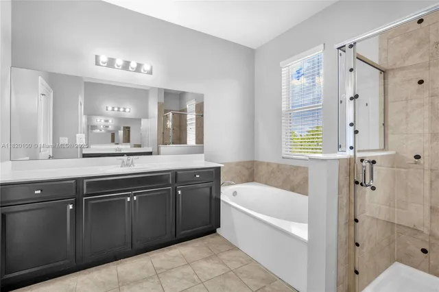 a bathroom with a tub a sink and a large mirror