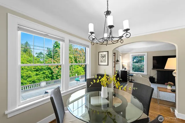 a view of a dining room with furniture a chandelier and large windows