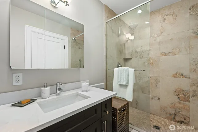 a bathroom with a sink vanity granite tub shower and a mirror