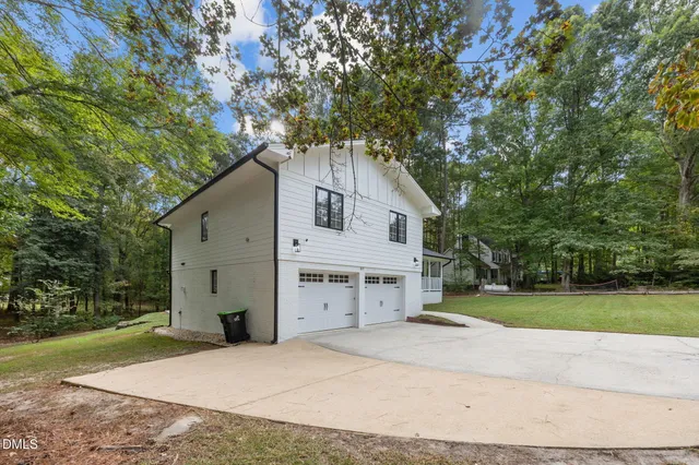 a view of a white house with a yard and large tree