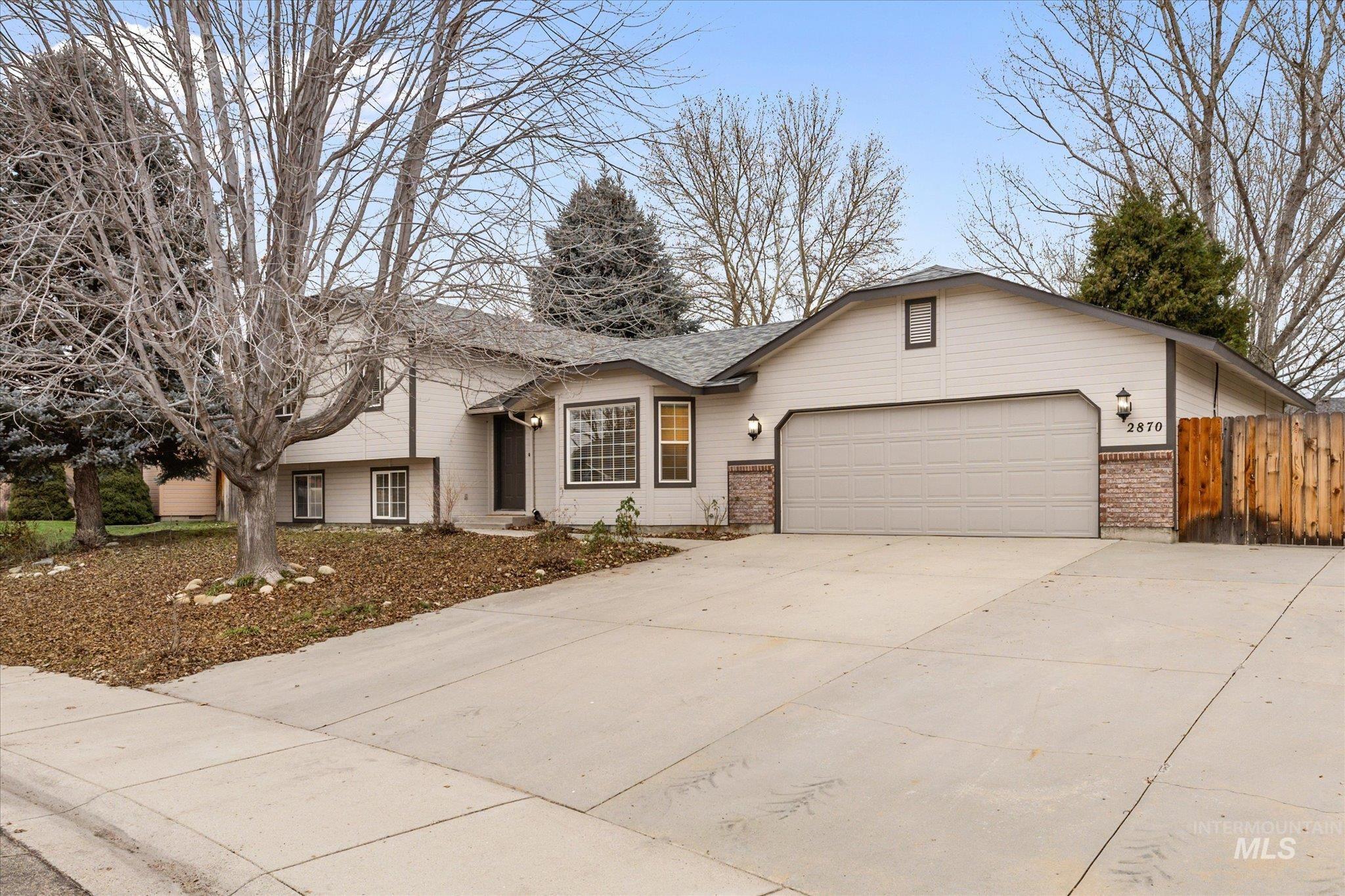 View of front of house with brick siding, concrete driveway, a garage, and a shingled roof