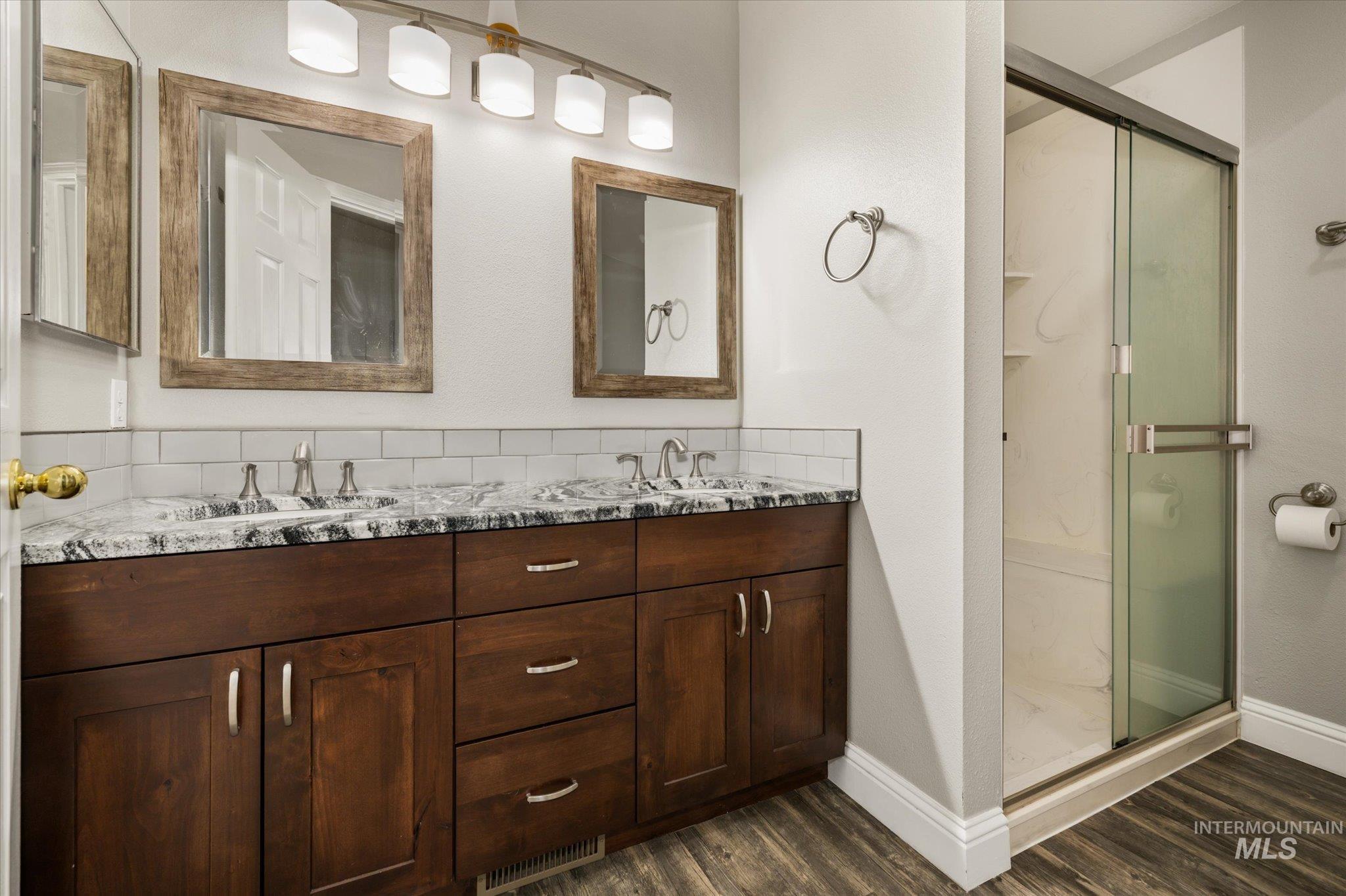 2870 North Morello Avenue Meridian, ID 83646 - Photo 5 of 20 Full bathroom featuring a shower stall, double vanity, and dark wood-style floors