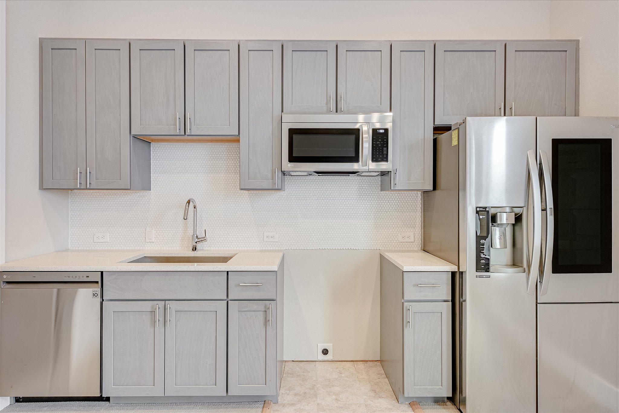 6136 Florencia Lane Austin, TX 78724 - Photo 21 of 40 Kitchen featuring stainless steel appliances, gray cabinets, tasteful backsplash, and light stone countertops
