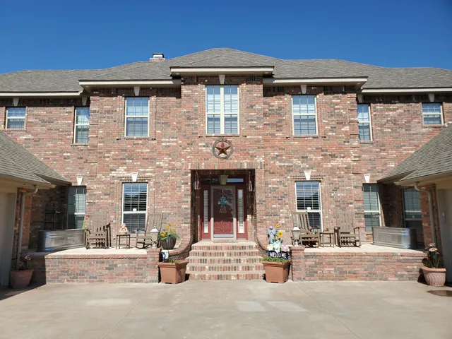a view of a brick house with potted plants and large windows