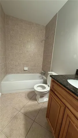 a bathroom with a granite countertop sink a toilet a mirror and bathtub