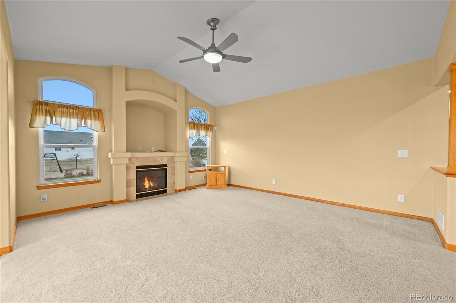 16231 Rayburn Street Hudson, CO 80642 - Photo 12 of 50 a view of an empty room with a fireplace and a chandelier fan